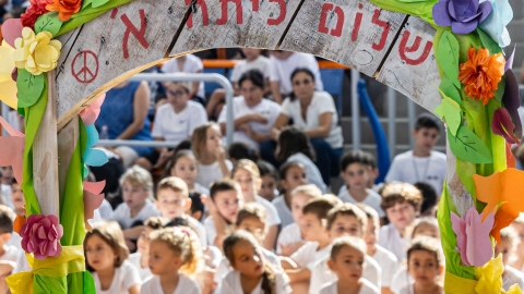תמונה של ילדים יושבים ומעליהם גשר שכתוב עליו שלום כיתה א.jpg