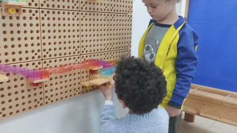 שני ילדים משחקים בלגו שתלוי על קיר.jpg