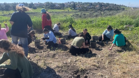 ילדים יושבים על האדמה עם כלי עבודה וחופרים.jpg