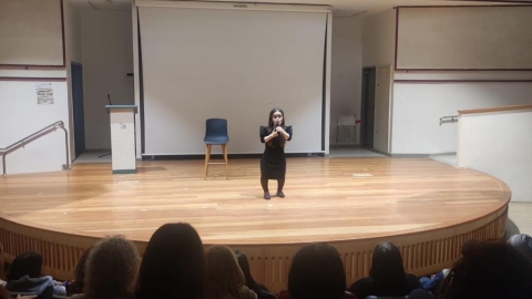 אישה עומדת על במה ומרצה.jpg