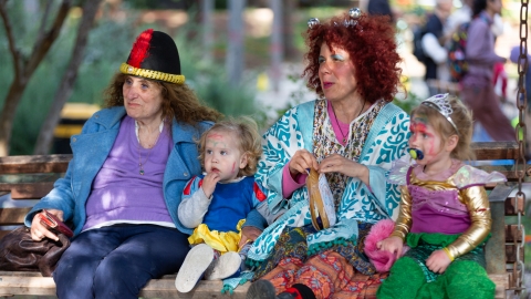 נשים וילדים מחופשים יושבים על נדנדה מעץ.jpg