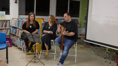 שתי נשים יושבות ושרות לידן גבר יושב ןמנגן בגיטרה.jpeg
