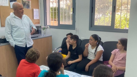 איש עומד ומסביבו ילדים יושבים.jpg