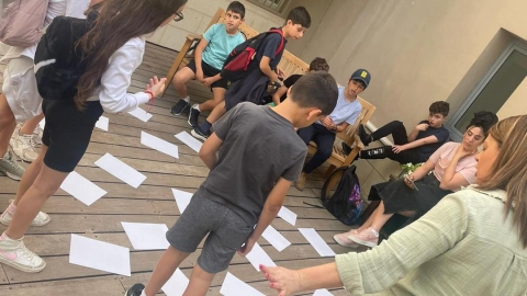 ילדים עומדים סביב דפים על הריצפה.jpg
