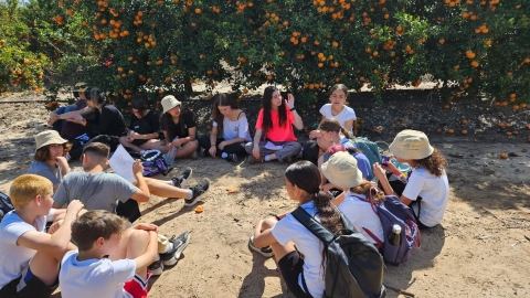 ילדים לובשים חולצות לבנות ויושבים במעגל ליד עצים.jpg