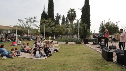 ילדים ונשים יושבים על דשא וצופים בהופעה.jpg