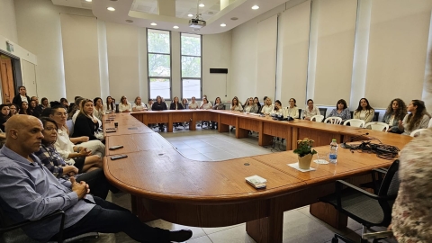 אנשים יושבים סביב שולחן בחדר ישיבות ומקשיבים להרצאה.jpg