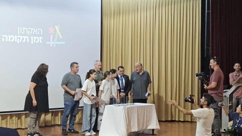 אנשים עומדים על במה ליד שולחן חלוקת תעודות.jpg