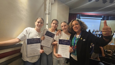 ארבע בנות עומדות מחובקות ומחזיקות בידיהן תעודות.jpg
