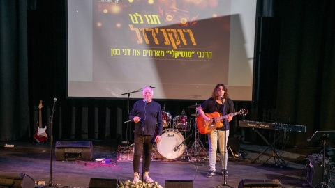 אנשים עומדים על במה אחד שר והשני מנגן בגיטרה.jpg