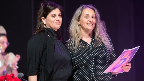 שתי נשים עומדות מחובקות. אחת מהן מחזיקה דף ביד.jpg