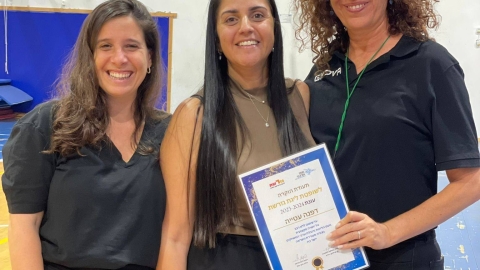 נשים עומדות ואחת מהן מחזיקה תעודה הוקרה.jpg