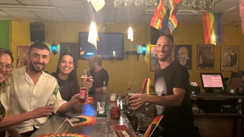 אנשים יושבים על הבר ומרימים כוס לחיים.jpg