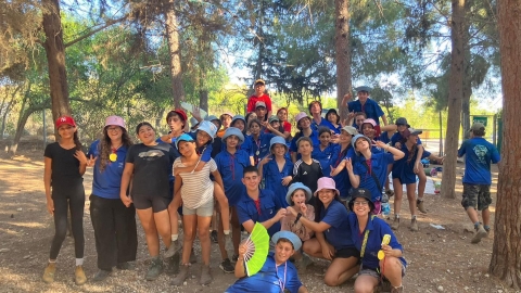 תמונה  של ילדים עומדים אחד ליד השני עם חולצה כחולה כחלק ממחנה בתנועות הנוער.jpg