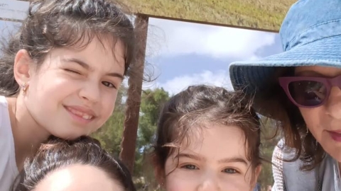 תמונה של שלוש בנות ואישה ומעליהן צילום של טרקטור בשדות.jpg