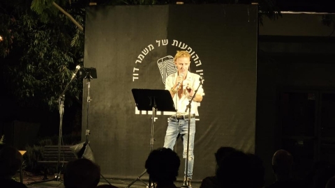 איש עומד על הבמה ומחזיקה מיקרופון.jpg