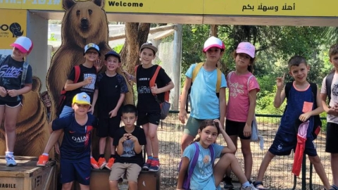 ילדים מצתלמים עם דמות דב ליד שלט שכתוב עליו כמה דב שבאתם.jpg