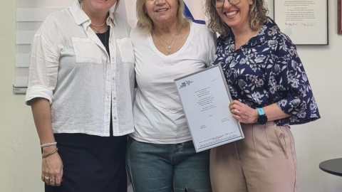 נשים עומדות ומתחבקות ואחת מהן מחזיקה מסגרת ביד.jpg