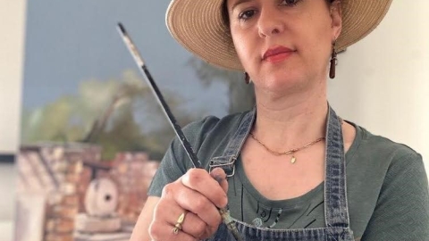 תמונה של אישה חובשת כובע ומחזיקה פלטה של צבעים ומכחול1.jpg