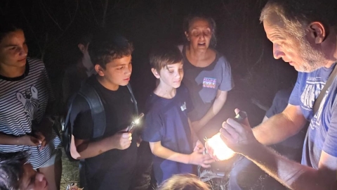 תמונה של ילדים סביב מדריך והמדריך מחזיק ביד פנס.jpg