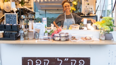 אישה עומדת בתוך הפודטראק שלה שנקרא פקל קפה.jpg