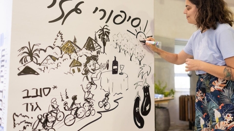 אישה מציירת על לוח שכתוב עליו סיפורי גזר.jpg