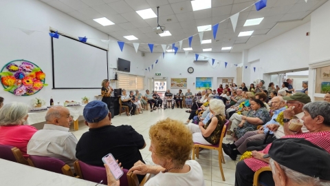 אנשים יושבים ואישה עומדת ומדברת למיקרופון.jpg