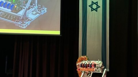 המייצג של הנבחרת עומד על במה ומאחוריו דגל ישראל.jpg