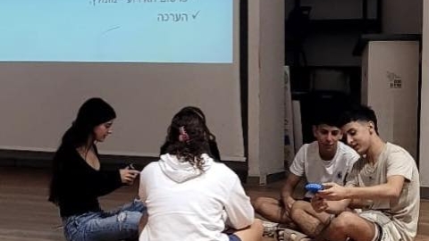 תלמידים יושבים במעגל על במה.jpg
