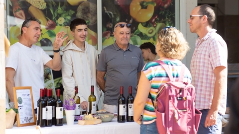 אנשים עומדים סביב שולחן ועליו יין.jpg