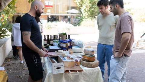 אנשים עומדים סביב דוכן גבינה וזיתים למכירה.jpg