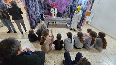 ילדים צופים בהצגה של שני שחקנים המחופשים למדענים.jpg