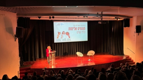 אישה עומדת על במה ונואמת.jpg