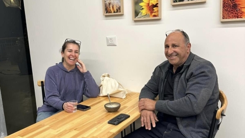 שני אנשים יושבים סביב שולחן ומחייכים.jpg