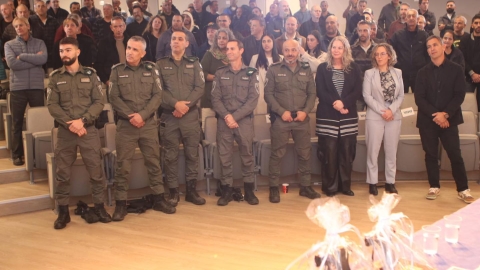 אנשים עומדים יחד בתוך אולם מופיעים. חלקם לובשי מדים של משמר הגבול.jpg