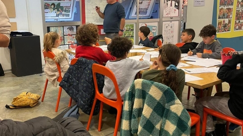 ילדים יושבים ומדריך מסביר להם על מייצגי הקומיקס.jpg