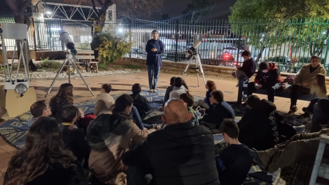 משפחות יושבות ברחבת אשכול הפיס ומקשיבות להרצאה על החלל ולומדות על הטלסקופ.jpg