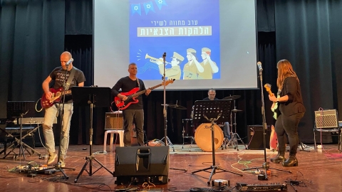 אנשים עומדים על במה ומנגנים בגיטרות.jpg