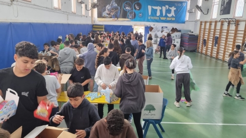 תלמידי כיתות ו אורזים משלוחי מנות באולם הספורט.jpeg