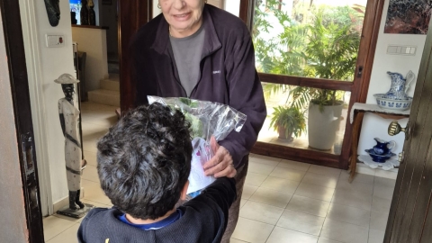 ילד מהגן נותן עציץ לתושבת ותיקה מהיישוב.jpg
