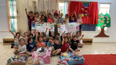 ילדי הגן בתמונה קבוצתית עם המשלוחים שהכינו עבור מחלקת הילדים ומחלקת הפגים בסורוקה.jpg