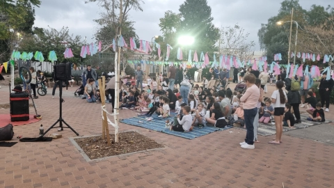 אנשים שהגיעו להפנינג יושבים על המחצלת לקראת המופע המרכזי.jpg