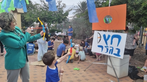 עמדת חץ וקשת בהפנינג ראשת המועצה רותם ידלין משחקת עם ילד בתחנה.jpg