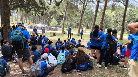 חניכי הנוער העובד והלומד יושבים ביער מקשיבים למדריך.jpg