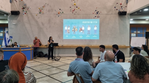 שרלי שוורץ מנהלת אגף דיגיטל מסבירה על תוכנית הערב ועל הדמויות שכל שולחן מייצג.jpg