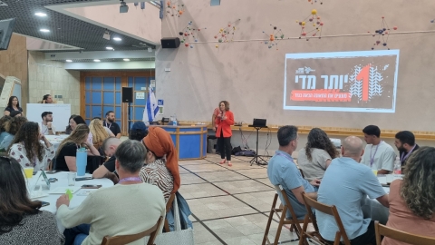 ראשת המועצה רותם ידלין נושאת דברים בפתיחת הערב על רקע המצגת אחד יותר מידי.jpg