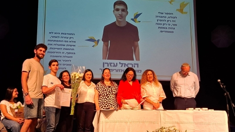 תמונה של הראל עזרן מוצגת בבימת הערב והראל על הבמה מקבל את הפרס.jpg
