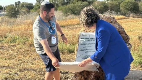 שני אנשים חושפים שלט על אבן.jpg