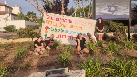 חניכי תנועת הנוער במצליח מחזיקים שלט עליו כתוב מצליח שומרים על החיים של כולם ומצייתים לכללי זהירות.j