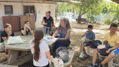 תלמידים יושבים ביחידה הסביבתית ולומדים ממנהלת היחידה נופר ששון עופר.jpg
